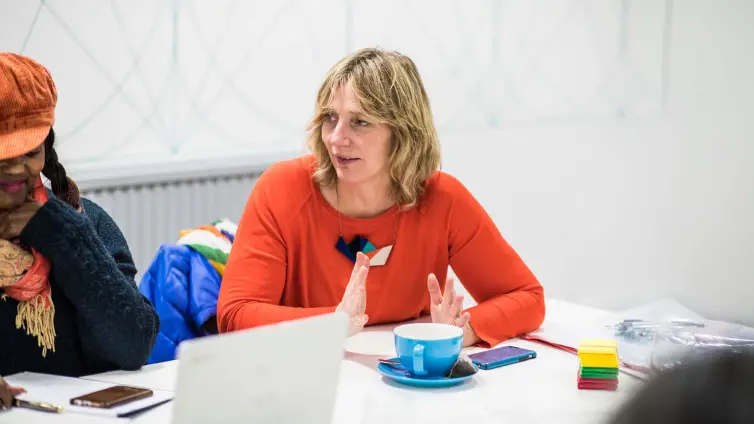 Two people sat at table, one talking to people out of shot.